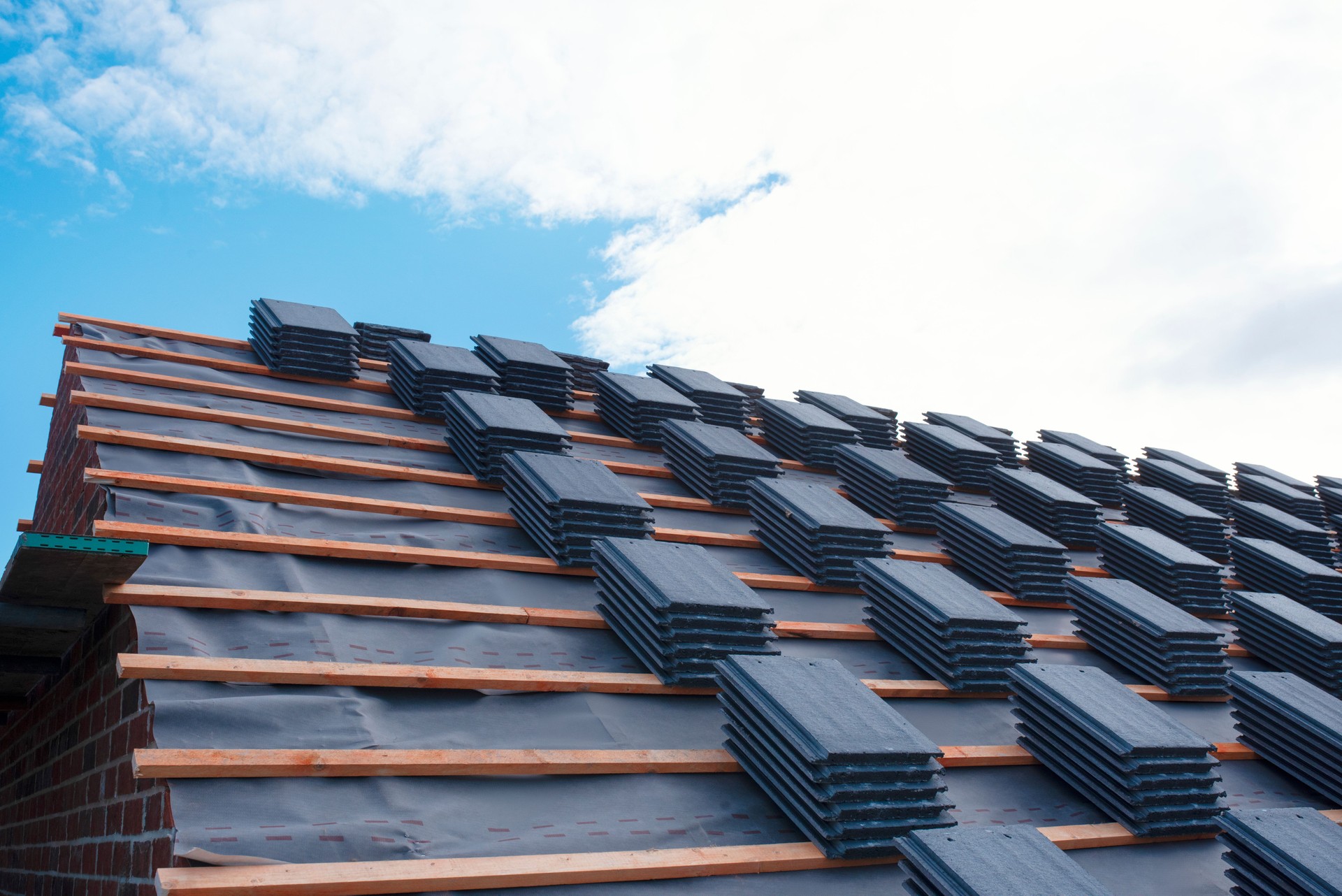 Roof Installation Process Captured on  Clear Day With New Tiles Awaiting Placement on a Building